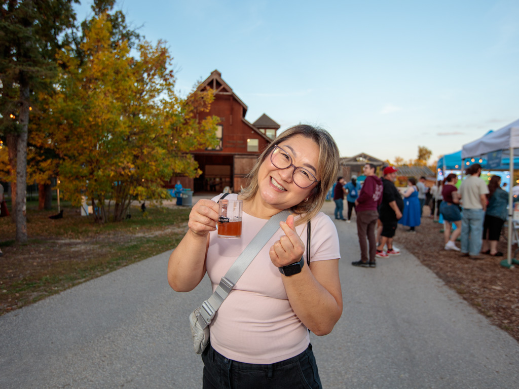 A Brew at the Zoo guest smiles to the camera holding a sample cup